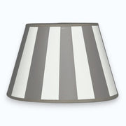 Ovaler Lampenschirm aus Stoff in Taupe und Weiß mit Streifendesign  auf hellem Hintergrund.