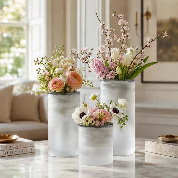Moderne Designvasen mit frischen Blumen in einem eleganten Wohnambiente mit heller, zeitloser Einrichtung.