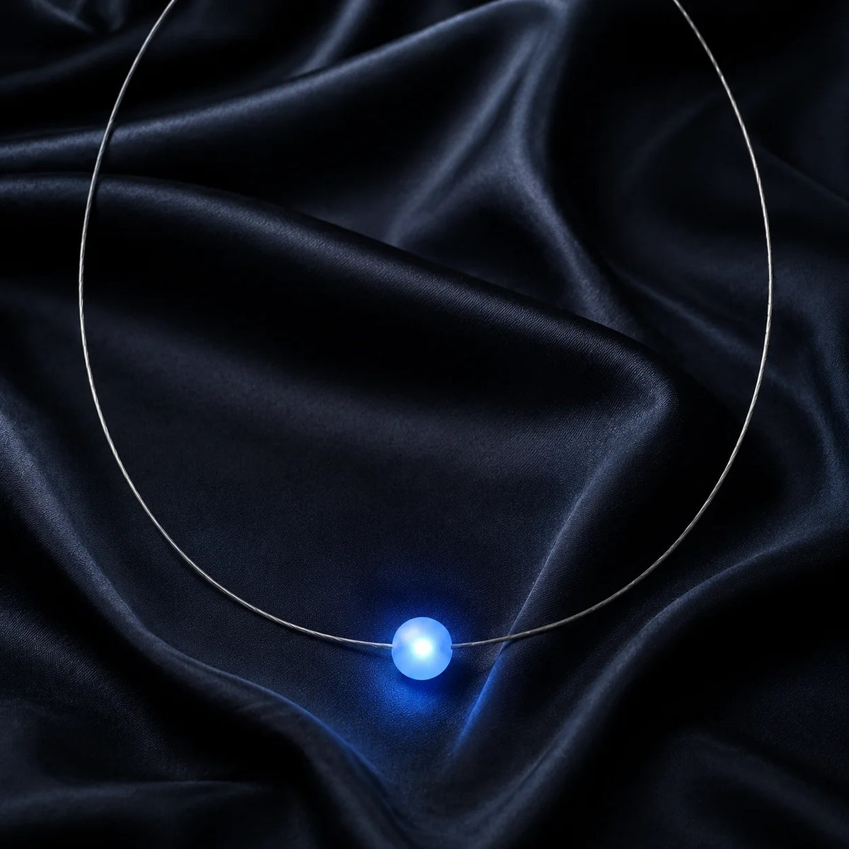 Firejewel LED-Halskette mit blau leuchtender Milchglaskugel luxuriös präsentiert auf schwarzer Seide