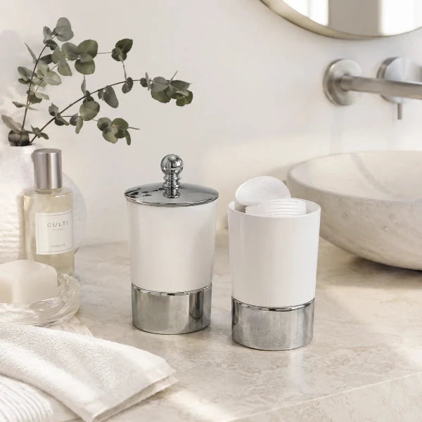 Moderne weiße Keramik-Kosmetikdose mit Chromdetails und Wattepads auf einem hellen Badezimmer-Waschtisch dekoriert.