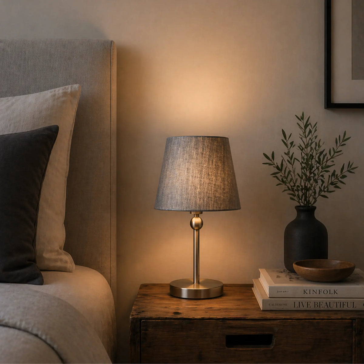 Grauer Stoff-Lampenschirm auf Nachttischlampe im Schlafzimmer mit warmem gedämpftem Licht und modernem Metallfuß