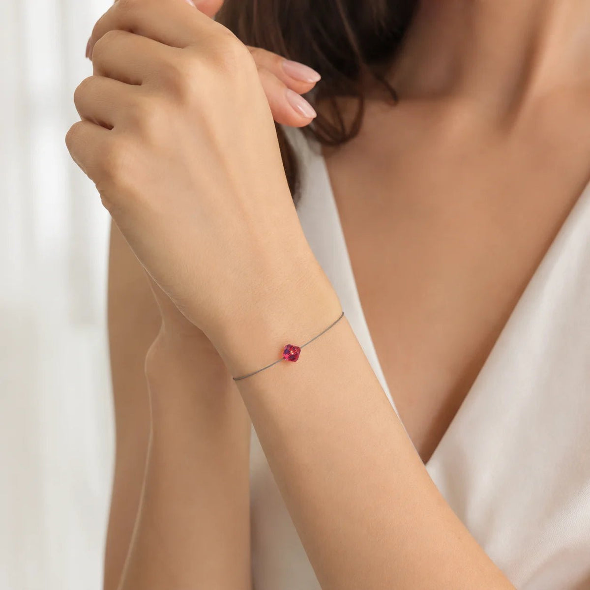 Frau trägt ein filigranes LED-Armband mit kleinem roten Swarovski® Kristall in Bicone-Form