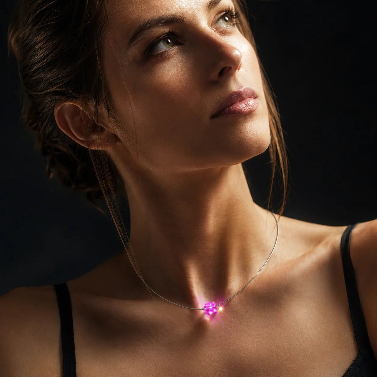Frau trägt eine leuchtende LED Halskette mit pinkfarbenem Kristall-Cube als modernes Schmuck-Highlight.