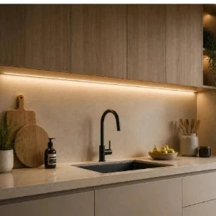 Moderne Küche mit warmer LED-Unterbauleuchte, Holzschränken, schwarzer Armatur und heller Arbeitsplatte