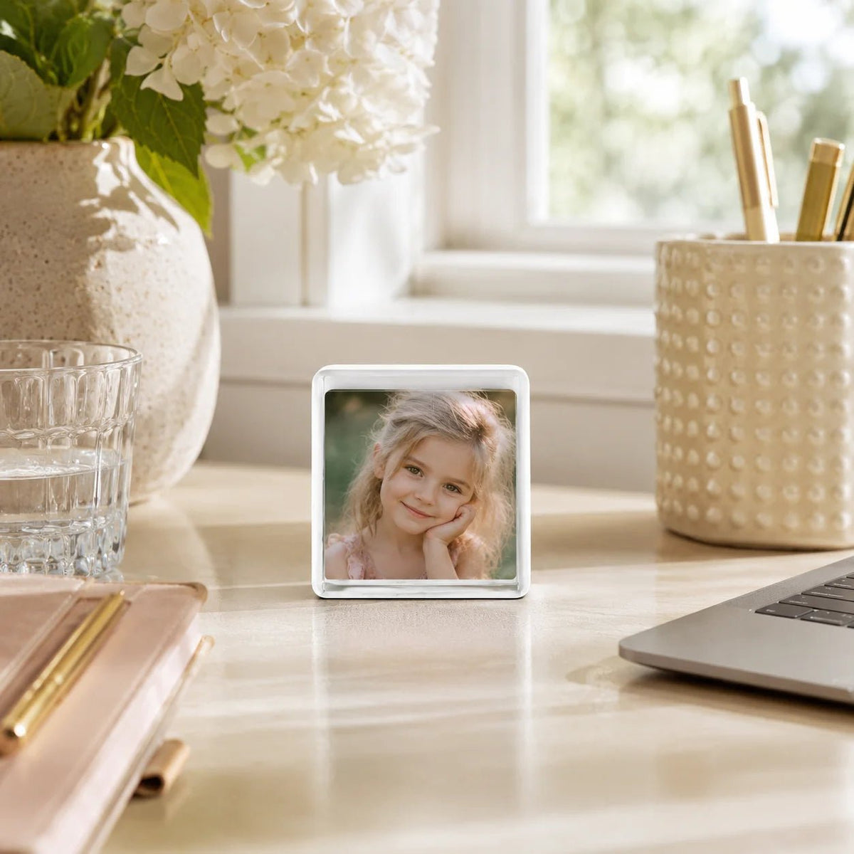 Sompex Mini-Bilderrahmen 5 × 5 cm aus Glas in Weiß mit Kinderfoto auf einem hellen Homeoffice-Schreibtisch